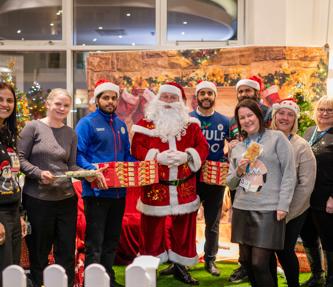 Hightown staff, Tesco staff and Santa smiling and holding mince pies