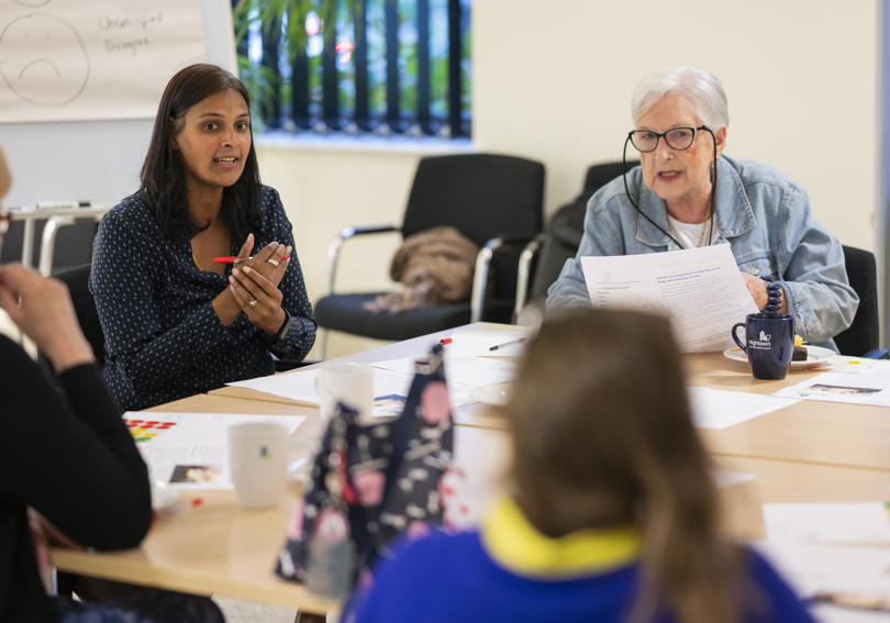 Hightown staff talking in a meeting about a complaints leaflet and how to make it more accessible. 