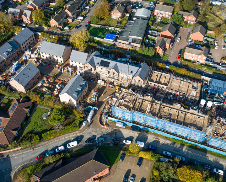 An aerial shot. One side shows houses which have been build and then other side shows a building site. 