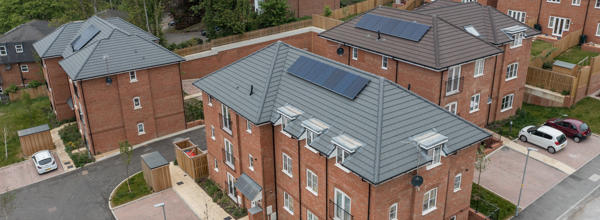 An aerial photo of new build flats and houses, with solar panels on the roof and parking spaces outside the properties. 