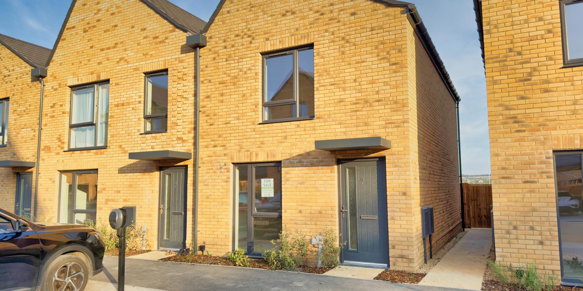 A slate grey front door with a large window downstairs and another large window positioned in the middle of the house on the first floor