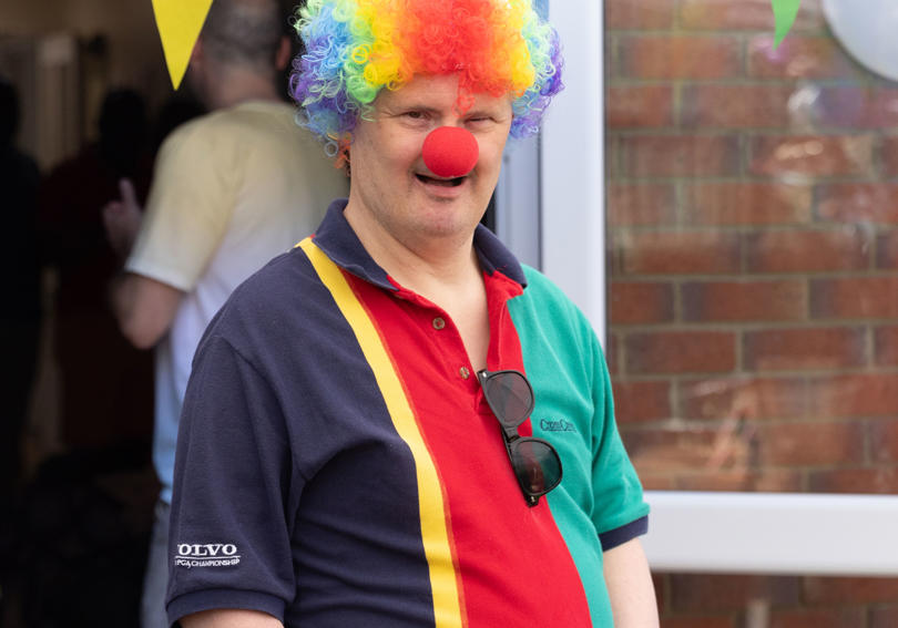 A service user dresses up in a clown wig and nose