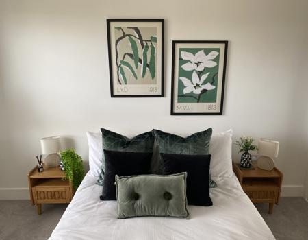 A double bed with oak bedside tables and green cushions