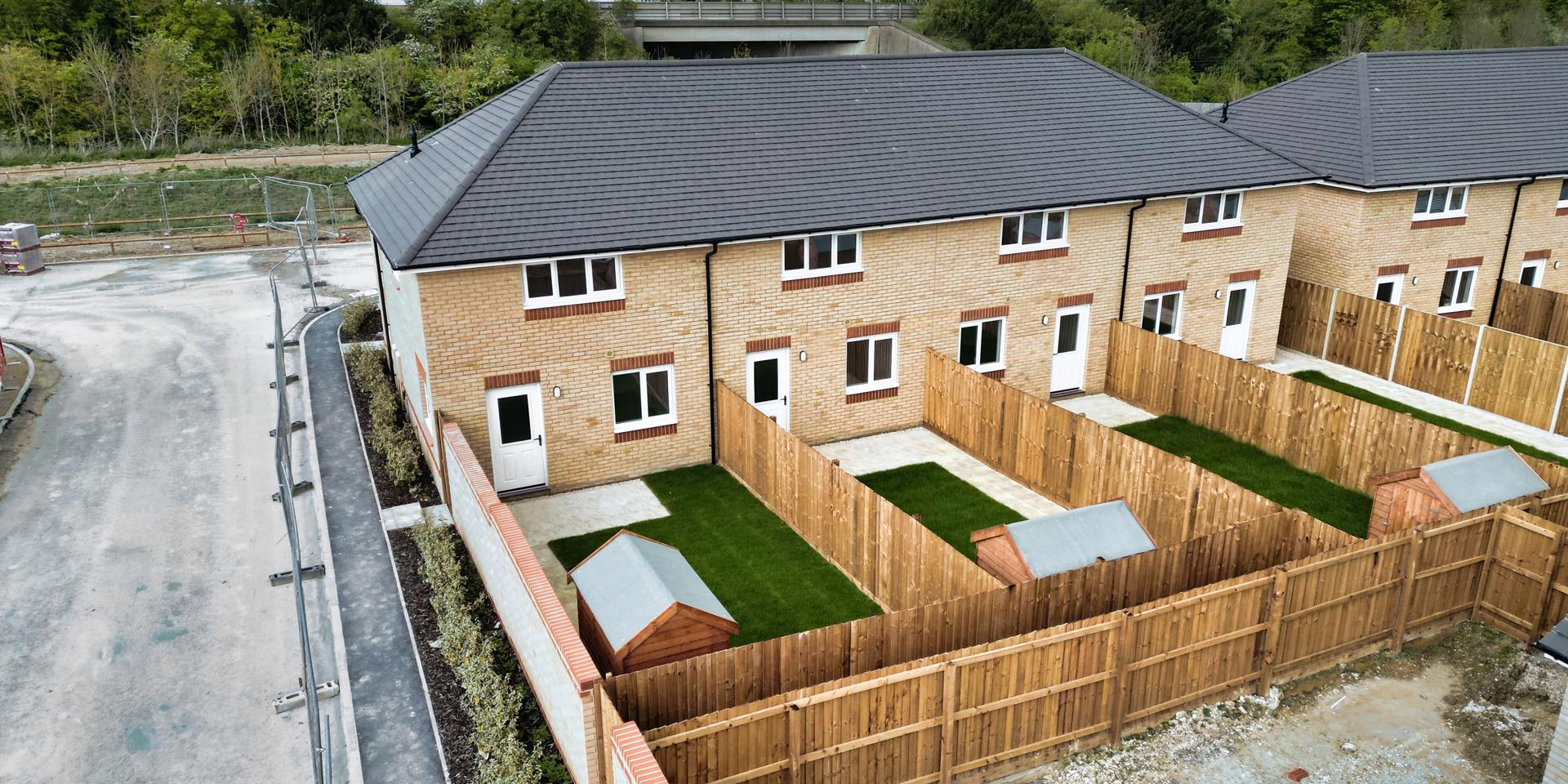 A birds-eye view of the rear gardens showing the sheds and patio areas