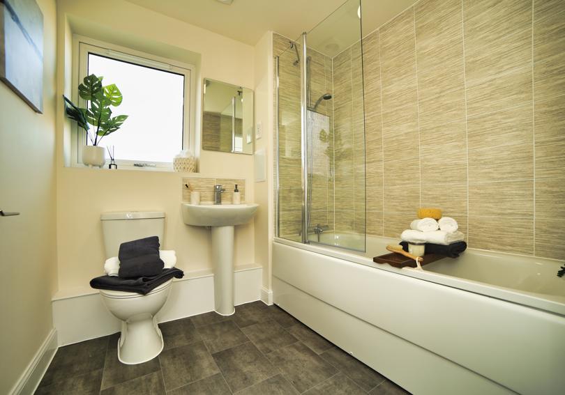 View of the bathroom including the bath with shower, toilet and wash hand basin