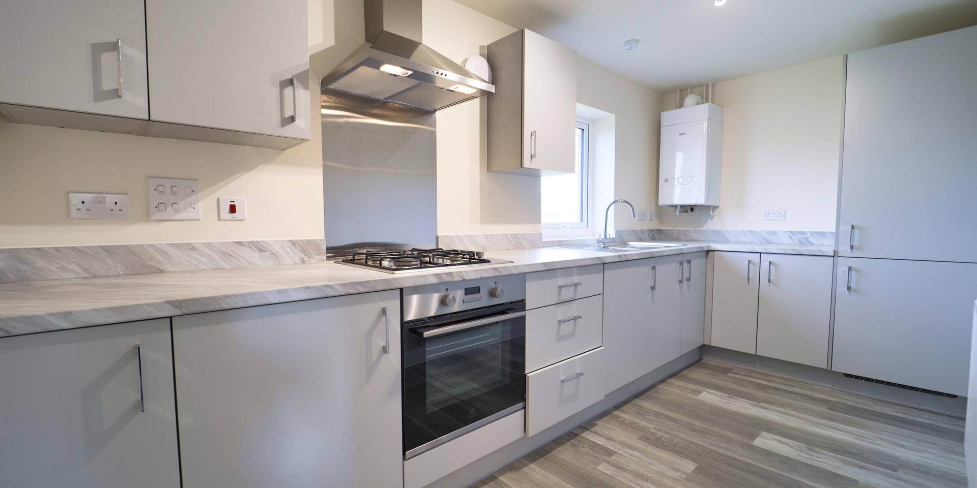 There are light grey fitted kitchen units and integrated appliances