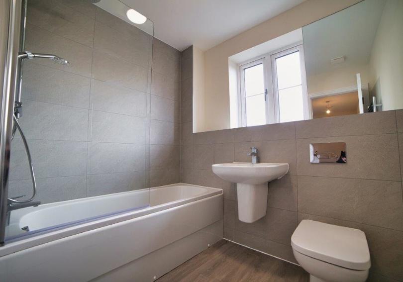 The bathroom with its shower over the bath, toilet and wash hand basin