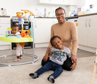 Hightown resident and her two children smiling and playing in the living area.