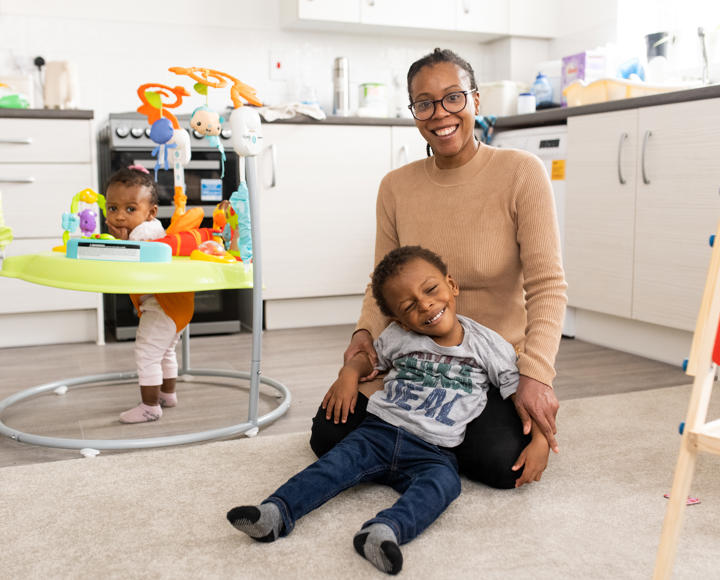 Hightown resident and her two children smiling and playing in the living area.