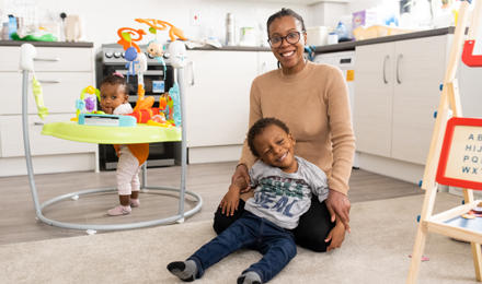 Hightown resident and her two children smiling and playing in the living area.