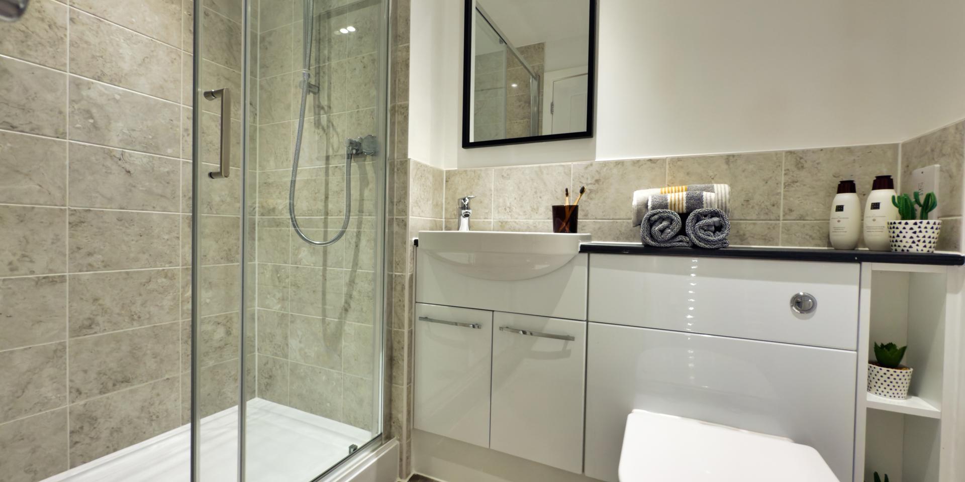 A white suite with enclosed shower cubicle with sliding glass doors