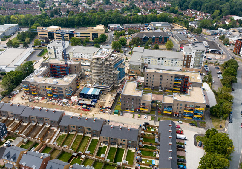 Aerial view of of a big new development, including flats and houses. 