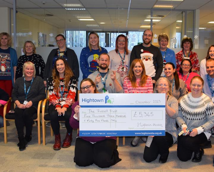Hightown staff members smiling and holding up a giant cheque for £5,345 to the Trussell Trust