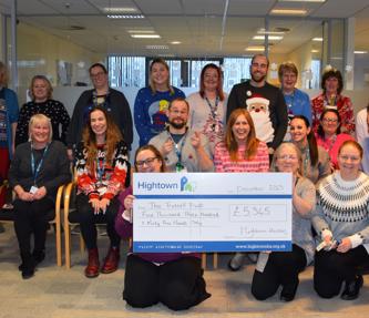 Hightown staff members smiling and holding up a giant cheque for £5,345 to the Trussell Trust