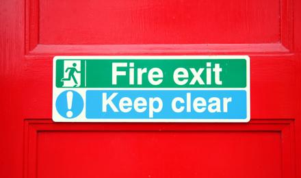 A fire exit and keep clear sign on a red door.