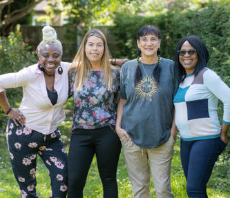 Four women smiling in a sunny garden