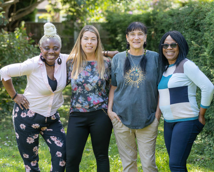 Four women smiling in a sunny garden