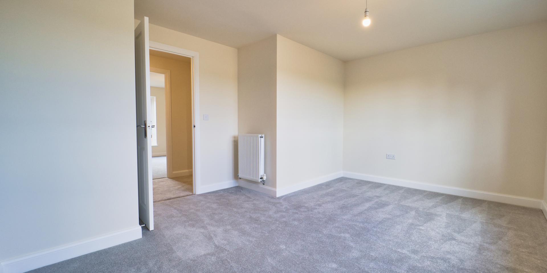 Light grey carpets and a small store cupboard positioned behind the bedroom door