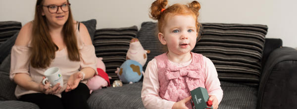 Hightown resident and her daughter who is holding a foam toy house, on the sofa, in their new home.