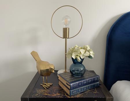 An oriental bedside table with lamp, books and bird ornament on it