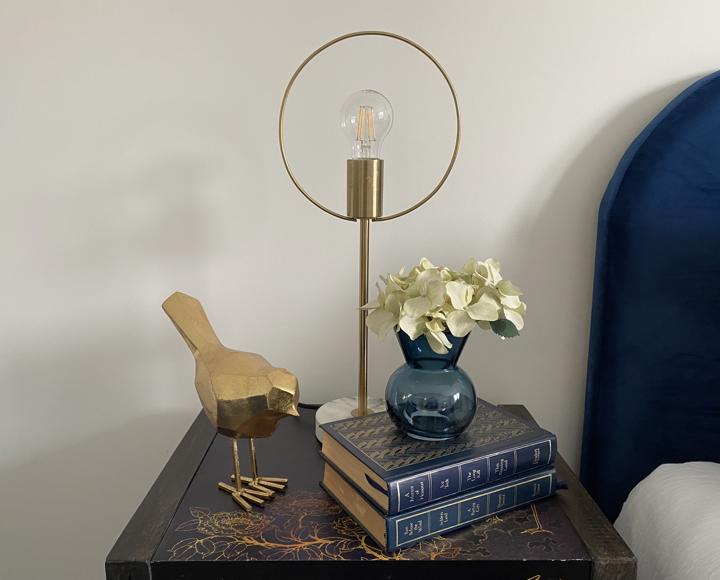 An oriental bedside table with lamp, books and bird ornament on it