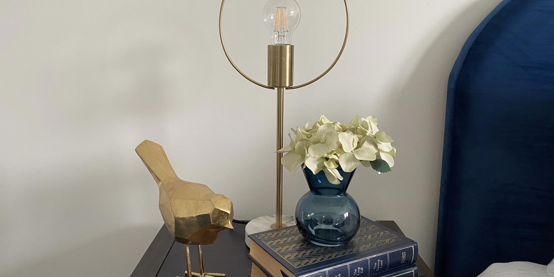 An oriental bedside table with lamp, books and bird ornament on it