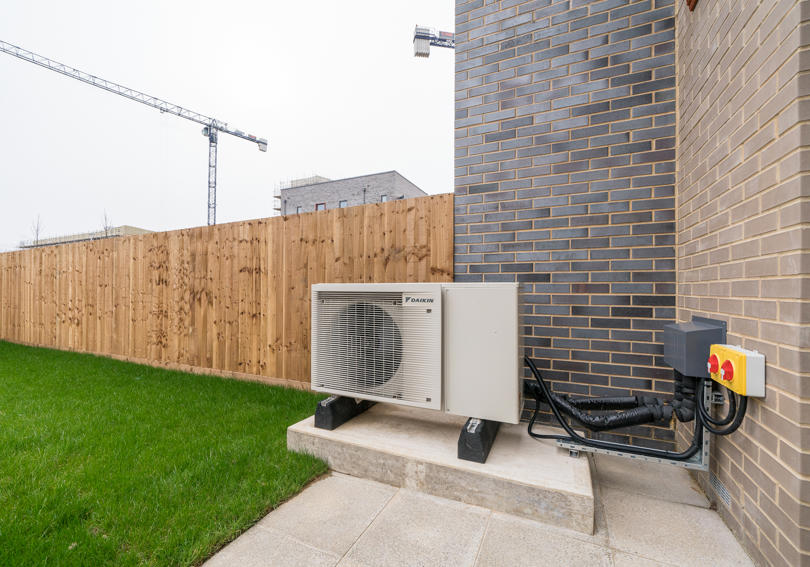 The air source heat pump is located outside the garden door