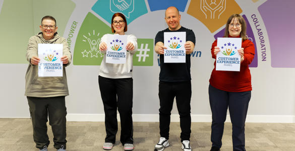 Three women and one man holidng up signs that read 'Customer Experience Panel'