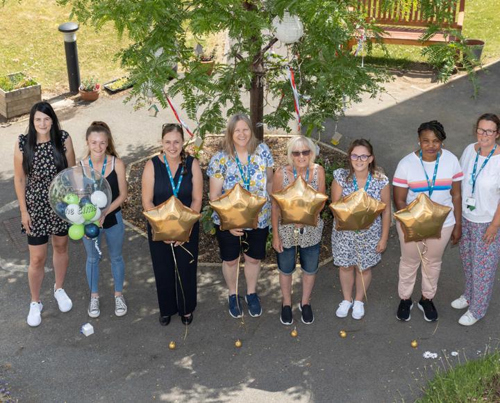 Staff celebrating and holding balloons after receiving an 'excellent' in an assessment by the local council 