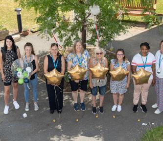 Staff celebrating and holding balloons after receiving an 'excellent' in an assessment by the local council 