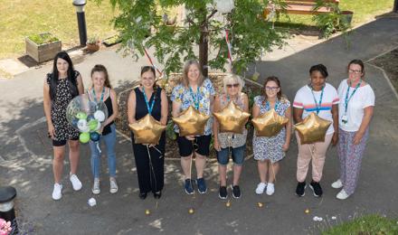 Staff celebrating and holding balloons after receiving an 'excellent' in an assessment by the local council 