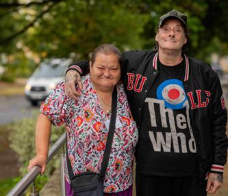 A man with his arms around the shoulders of a woman standing outside