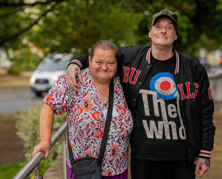 A man with his arms around the shoulders of a woman standing outside