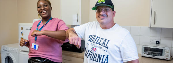 Hightown staff member and service user smiling inside a kitchen.