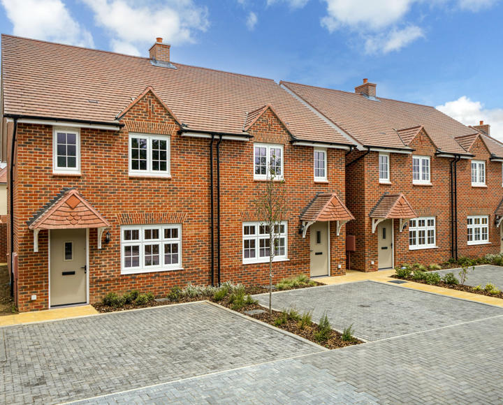 A row of houses, with their own parking space outside.