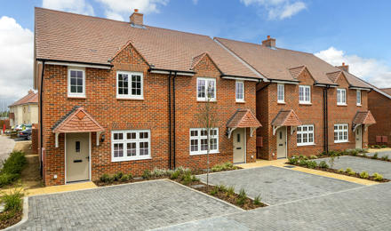 A row of houses, with their own parking space outside.